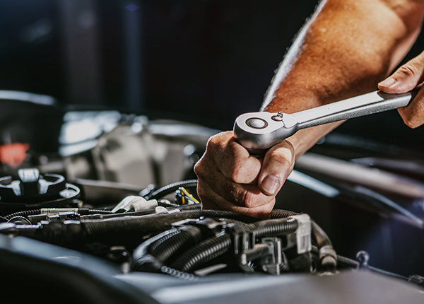 A man working on a car in a garage that is covered by garage keepers liability insurance.